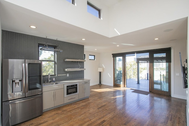 kitchen featuring a sink, wood finished floors, oven, and stainless steel fridge with ice dispenser