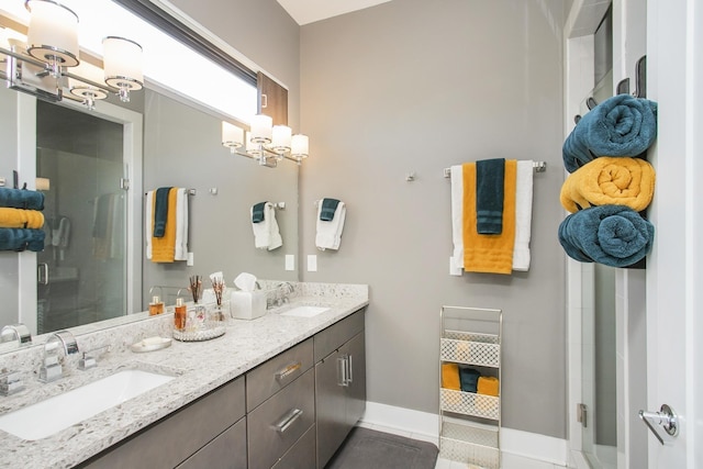 bathroom with double vanity, a stall shower, baseboards, and a sink