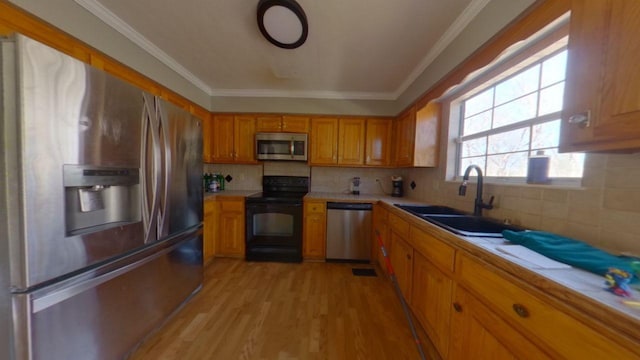 kitchen featuring a sink, stainless steel appliances, light wood-style floors, and light countertops