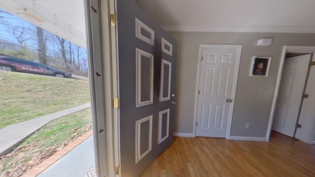 foyer with baseboards, light wood-style flooring, and ornamental molding