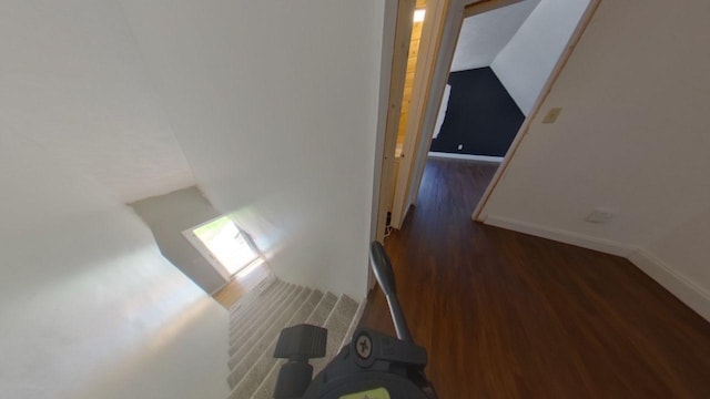 hallway with baseboards, wood finished floors, and vaulted ceiling