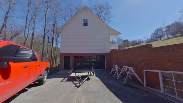 view of side of home featuring brick siding, an attached garage, and fence