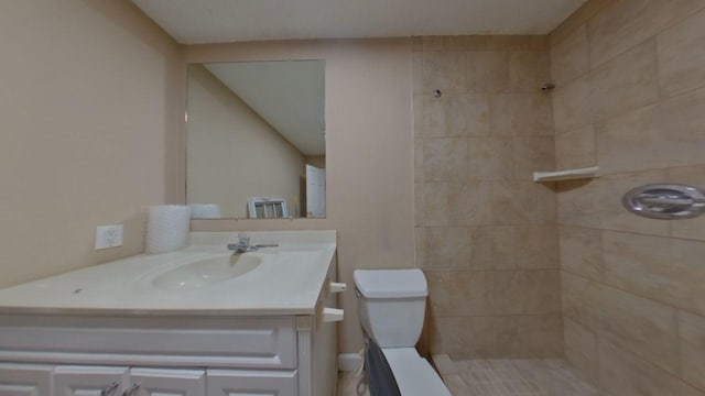 bathroom featuring tiled shower, toilet, and vanity