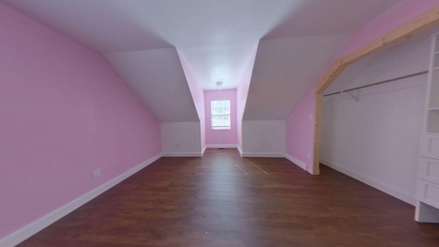 additional living space with dark wood finished floors, lofted ceiling, and baseboards