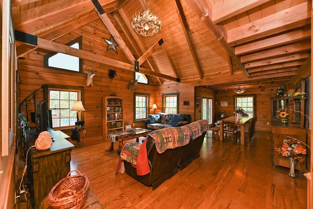 living room featuring wooden walls, beamed ceiling, wood ceiling, an inviting chandelier, and wood-type flooring