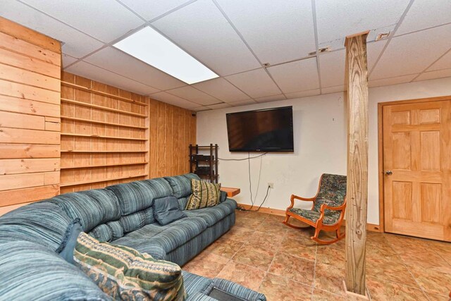 living room with built in shelves, a paneled ceiling, and baseboards