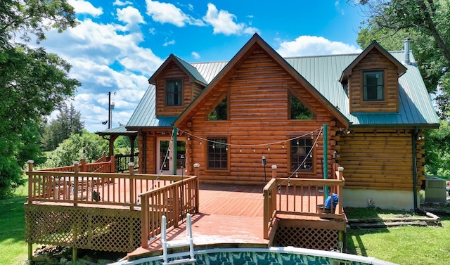 rear view of house with log siding, a wooden deck, metal roof, and a yard