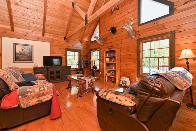 living room with beam ceiling, wooden walls, wood finished floors, and high vaulted ceiling