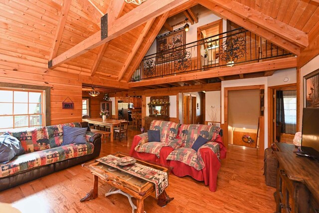 living area featuring beam ceiling, wood ceiling, and wood finished floors