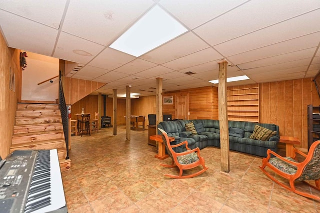 living area featuring stairway, wooden walls, and a paneled ceiling