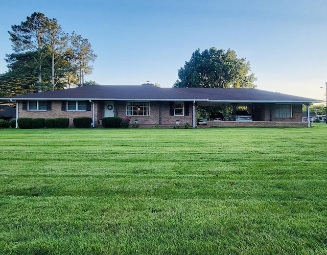 ranch-style house with a carport, brick siding, and a front yard