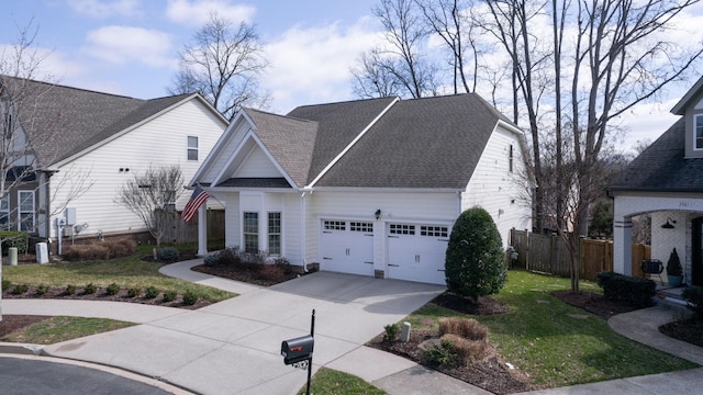 view of front facade featuring an attached garage, concrete driveway, a front yard, and fence