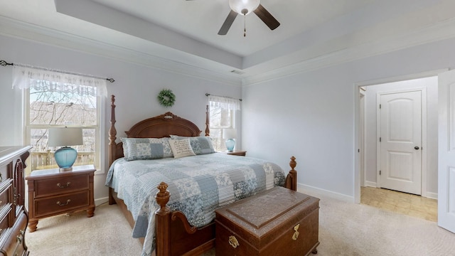 bedroom featuring baseboards, multiple windows, a raised ceiling, and light carpet