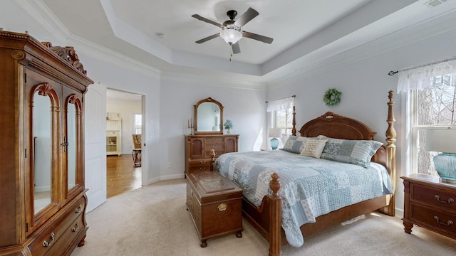 bedroom with a tray ceiling, light carpet, baseboards, and ceiling fan