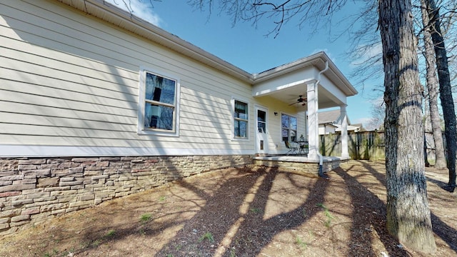 view of side of property featuring fence and ceiling fan