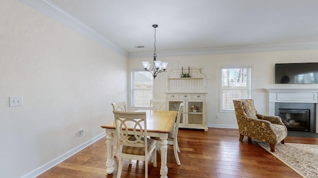 dining area featuring a notable chandelier, ornamental molding, baseboards, and hardwood / wood-style flooring