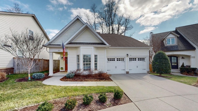 view of front of house with concrete driveway, an attached garage, fence, and a front yard