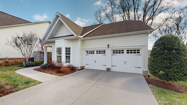 view of front of property with an attached garage, roof with shingles, and driveway