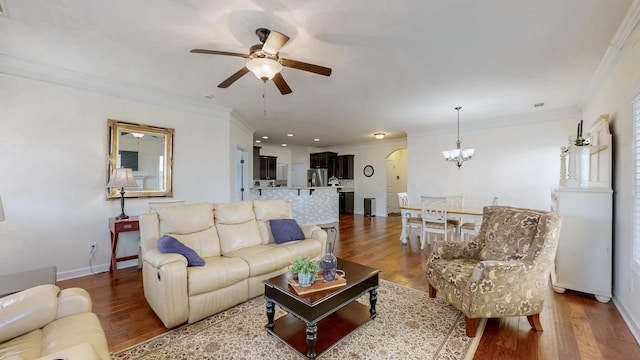 living room featuring baseboards, wood finished floors, crown molding, and ceiling fan with notable chandelier