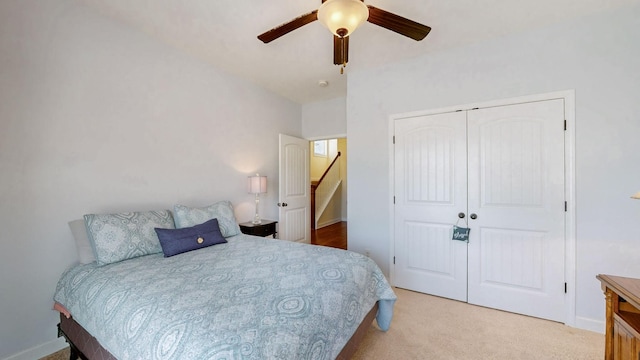 bedroom with a closet, light carpet, baseboards, and ceiling fan