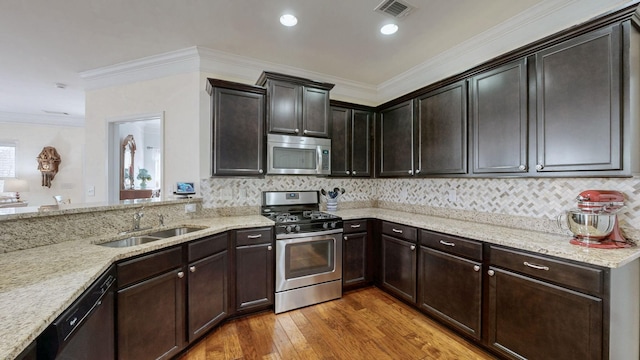 kitchen featuring visible vents, crown molding, light stone countertops, appliances with stainless steel finishes, and a sink