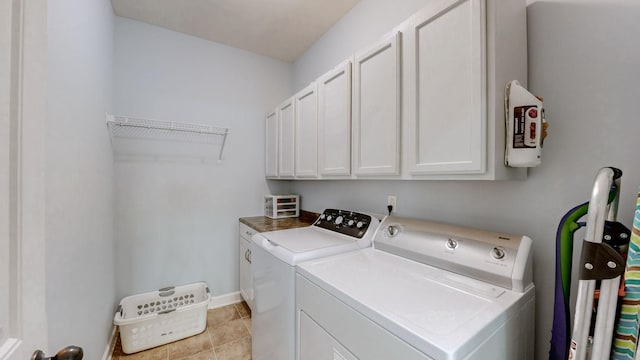 clothes washing area with light tile patterned floors, baseboards, cabinet space, and washing machine and clothes dryer