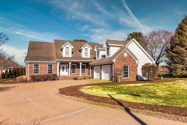 cape cod house featuring a garage, brick siding, concrete driveway, and a front yard