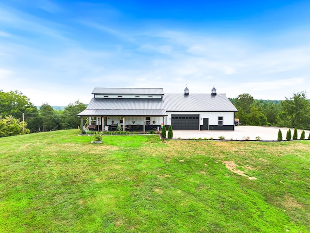 view of front facade with metal roof, driveway, an attached garage, and a front yard