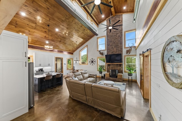 living area with wooden ceiling, a barn door, a ceiling fan, and concrete flooring