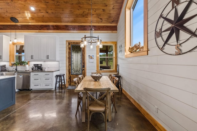 dining area with baseboards, an inviting chandelier, finished concrete floors, and wood walls