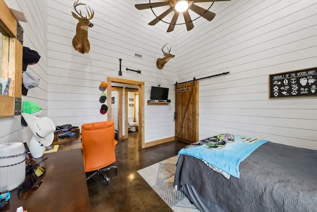 bedroom with a barn door, a high ceiling, and concrete floors