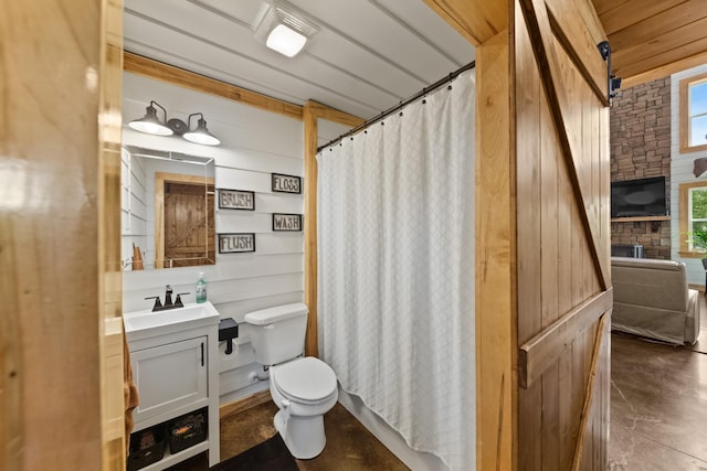 bathroom featuring curtained shower, toilet, wood walls, and vanity