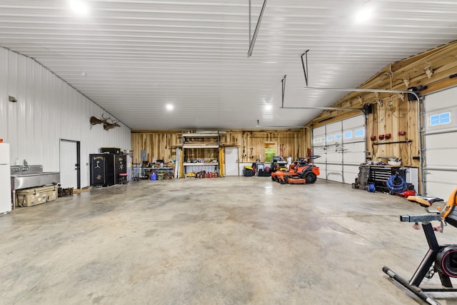 garage featuring a workshop area, metal wall, and freestanding refrigerator