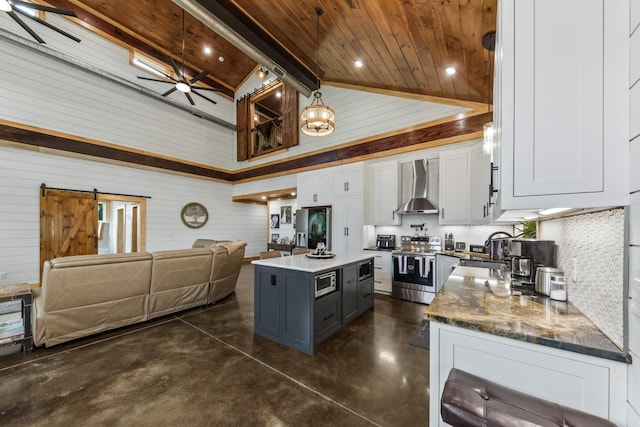 kitchen featuring stainless steel appliances, white cabinets, a barn door, wall chimney exhaust hood, and open floor plan