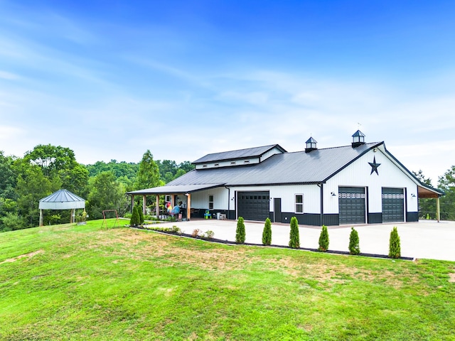 view of side of home with a lawn, metal roof, a detached garage, and a standing seam roof