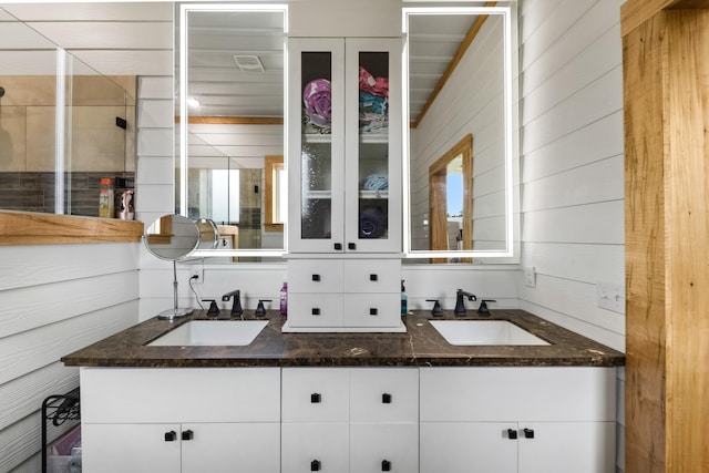 bathroom featuring double vanity, a shower stall, and a sink