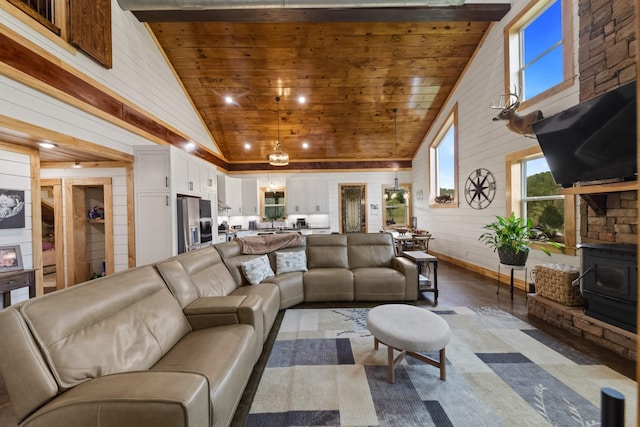 living room with baseboards, wood walls, wooden ceiling, a wood stove, and high vaulted ceiling