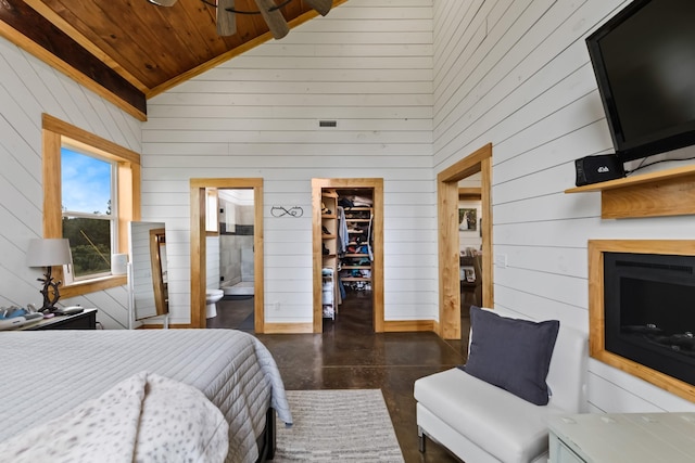 bedroom featuring a walk in closet, high vaulted ceiling, connected bathroom, concrete floors, and wood ceiling