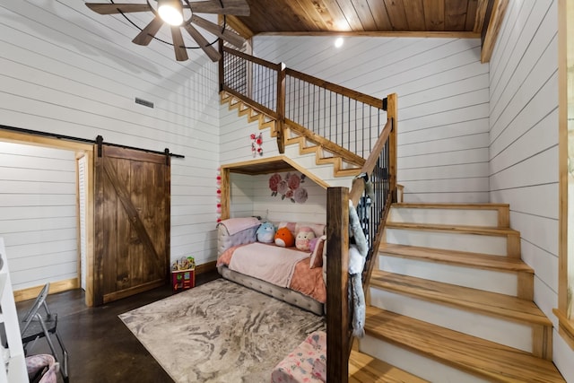 bedroom with wooden walls, visible vents, finished concrete floors, a barn door, and a towering ceiling