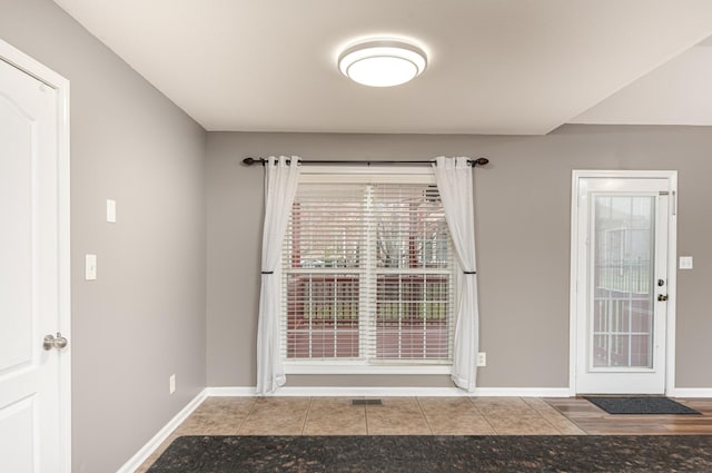 doorway to outside with tile patterned floors, visible vents, and baseboards