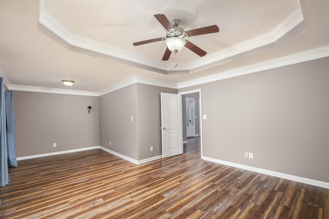 unfurnished room with a raised ceiling, crown molding, wood finished floors, and baseboards