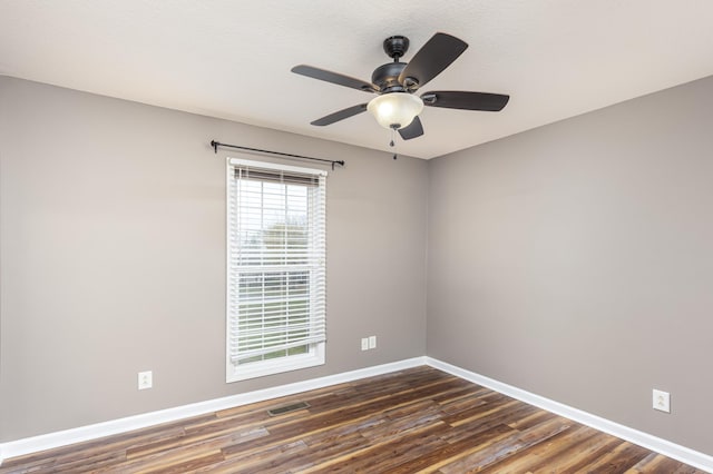 unfurnished room featuring visible vents, a ceiling fan, dark wood-type flooring, and baseboards