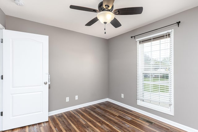 empty room with baseboards, visible vents, dark wood-style flooring, and ceiling fan