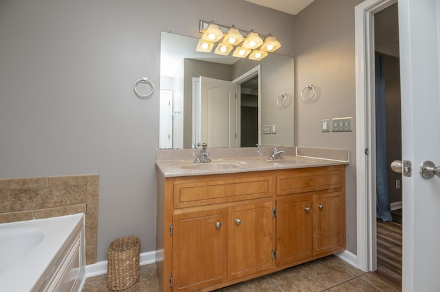 bathroom with baseboards, double vanity, a sink, tile patterned floors, and a bath