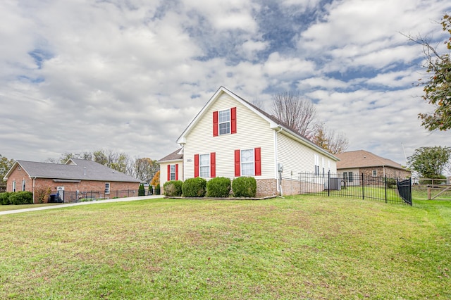 view of side of property with brick siding, a lawn, and fence