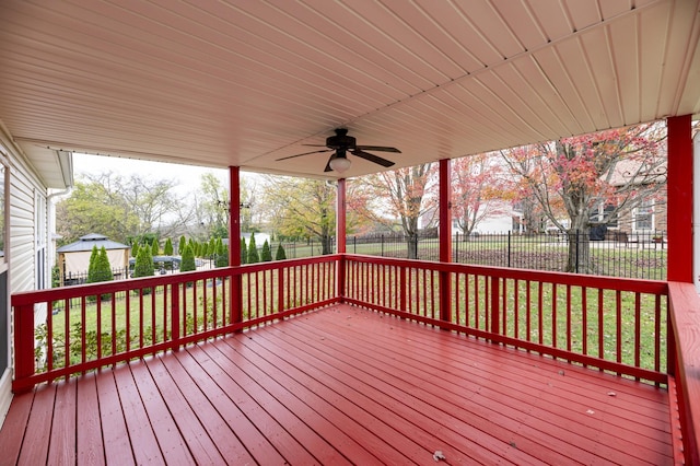 wooden terrace featuring a ceiling fan, a lawn, and a fenced backyard