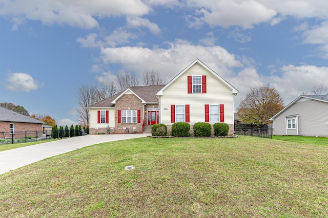 traditional home featuring brick siding, a front yard, and fence