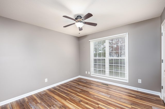 empty room with visible vents, a ceiling fan, baseboards, and wood finished floors