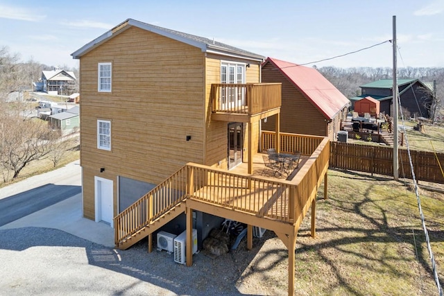 back of house with driveway, a balcony, and fence