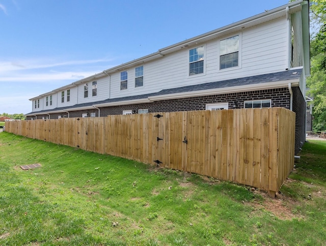 exterior space featuring a yard, brick siding, and fence